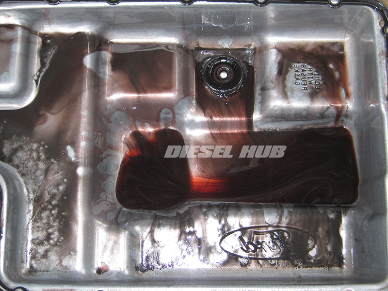 Dirty transmission pan with lots of clutch material and metal pieces
